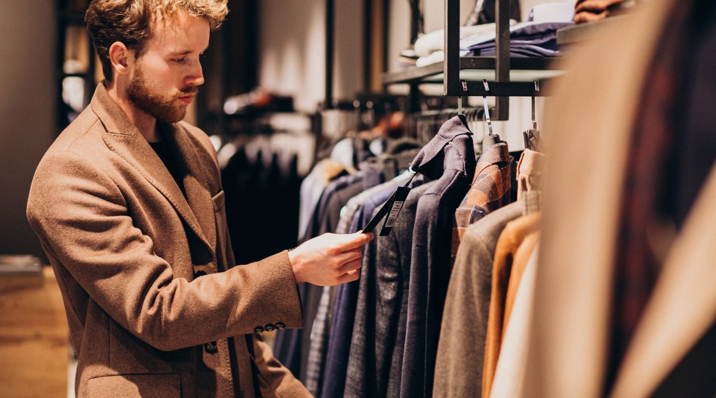 Young handsome man choosing cloth at shop